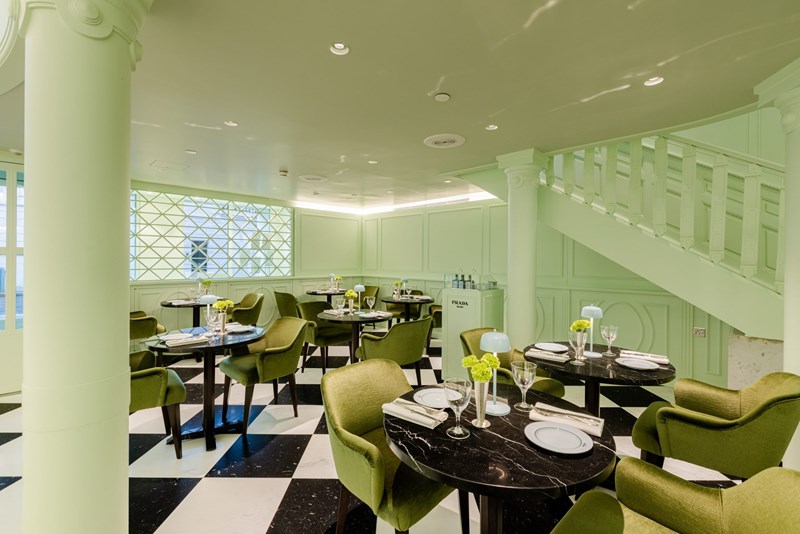 sala_tou_cafe_prada_me_fystiki_toixous_prasines_karekles_kai_mavra_marmarina_trapezia
