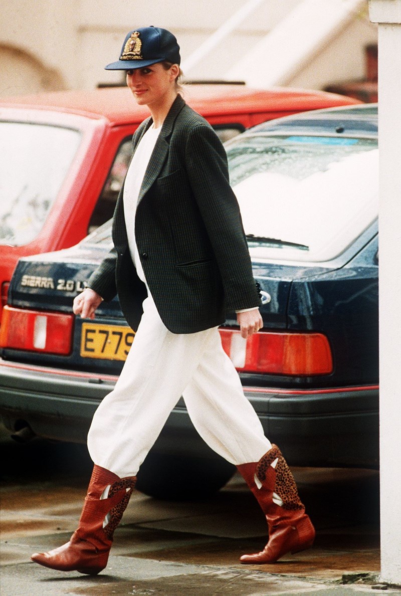 Princess Diana wearing an unusual combination of white trousers, boots, a blazer jacket and a baseball cap after taking her sons to school at Wetherby, 25th April 1989.