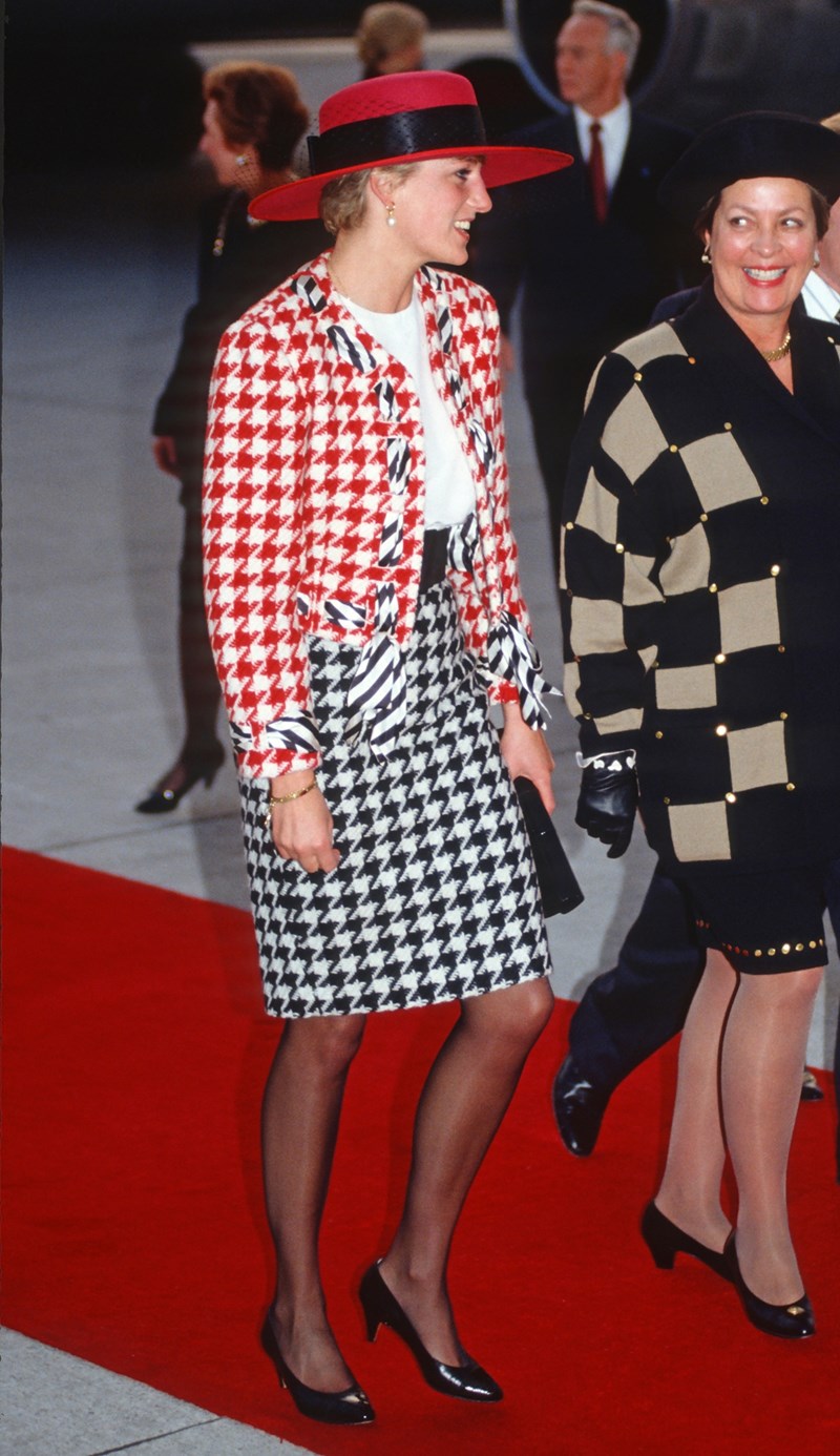 Diana, Princess of Wales, wearing a red and black houndstooth suit designed by Moschino and a red hat with black netting designed by Philip Somerville, arrives at Toronto Airport on October 23, 1991 in Toronto, Canada.